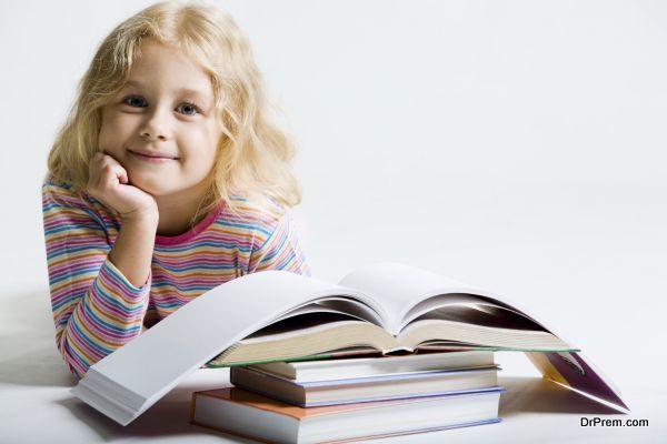 Portrait of little schoolgirl smiling from behind books on a white background