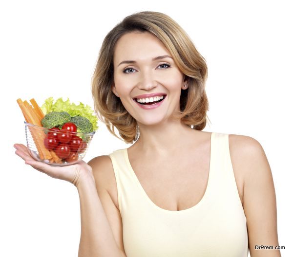 Portrait of a young smiling woman with a plate of vegetables - isolated on white.