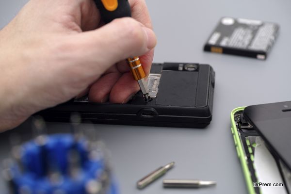 Man repairing cellphone with screwdriver. Cellphones have dust, dirt and  scratches.
