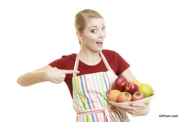 Diet and nutrition. Happy housewife or chef in striped kitchen apron offering healthy fruit isolated