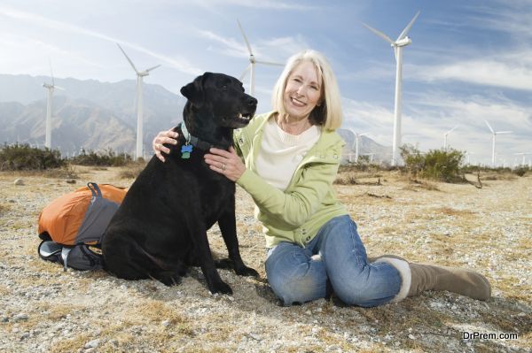 Portrait of a beautiful senior woman sitting with pet dog during vacation at wind farm