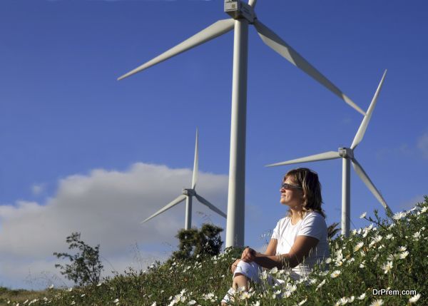 young woman dreams about the future on a wind farm beneath eolic generator