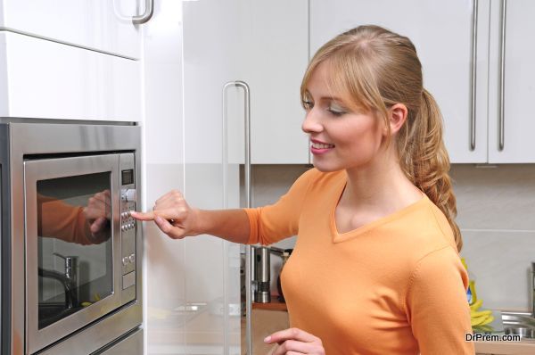 Blond woman cooks with a microwave in a modern kitchen