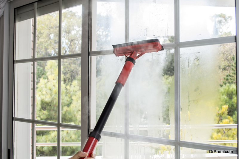 woman cleaning window glass with steam