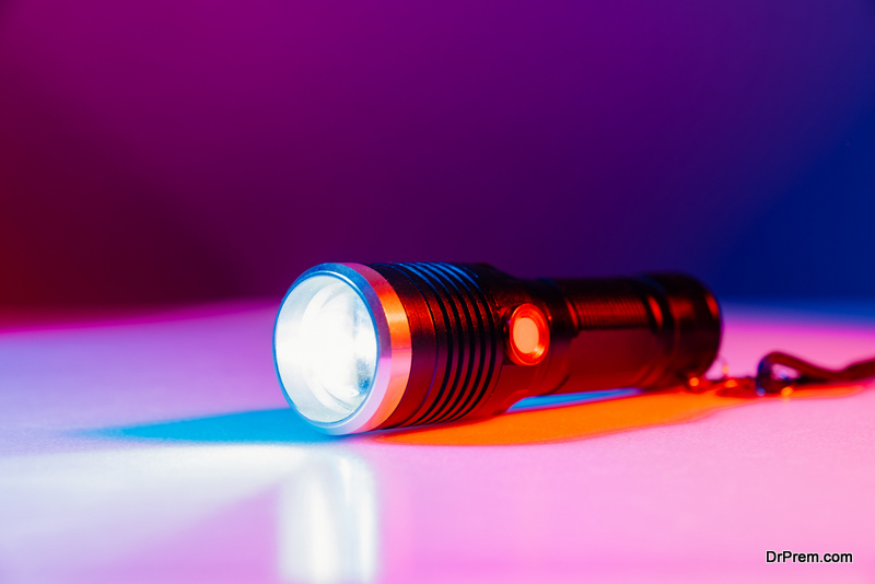 A small black flashlight in colored lighting