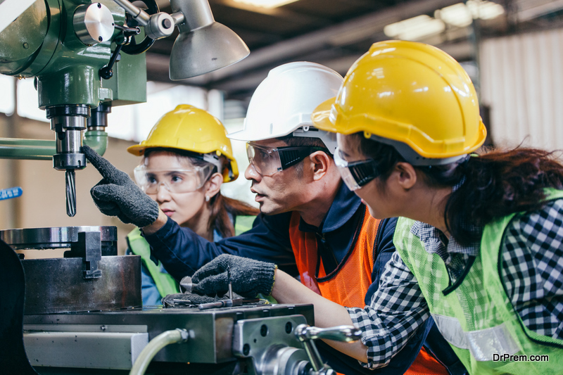 Asian male technician manager showing case study of factory machine to two engineer trainee 